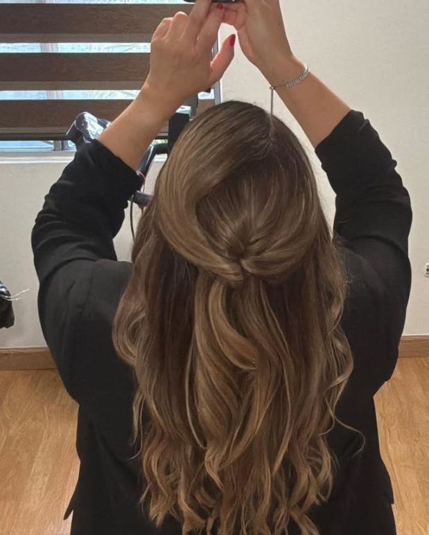 Estilista terminando un semirecogido con ondas